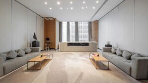 A modern living room with two sofas, a coffee table, a kitchen area, and a large window providing natural light.