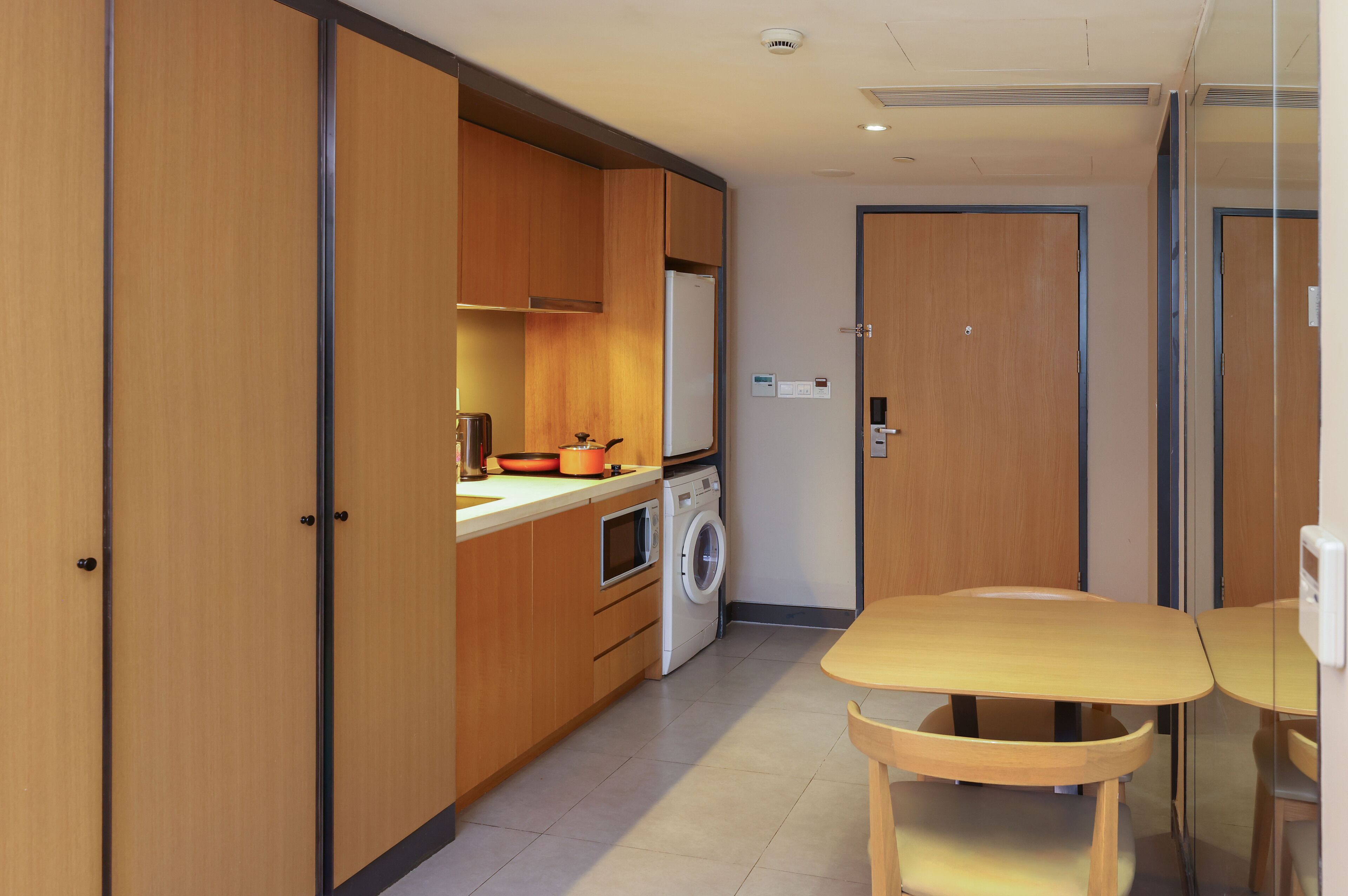 Une cuisine compacte avec des meubles de rangement en bois, un lave-linge et une petite table.