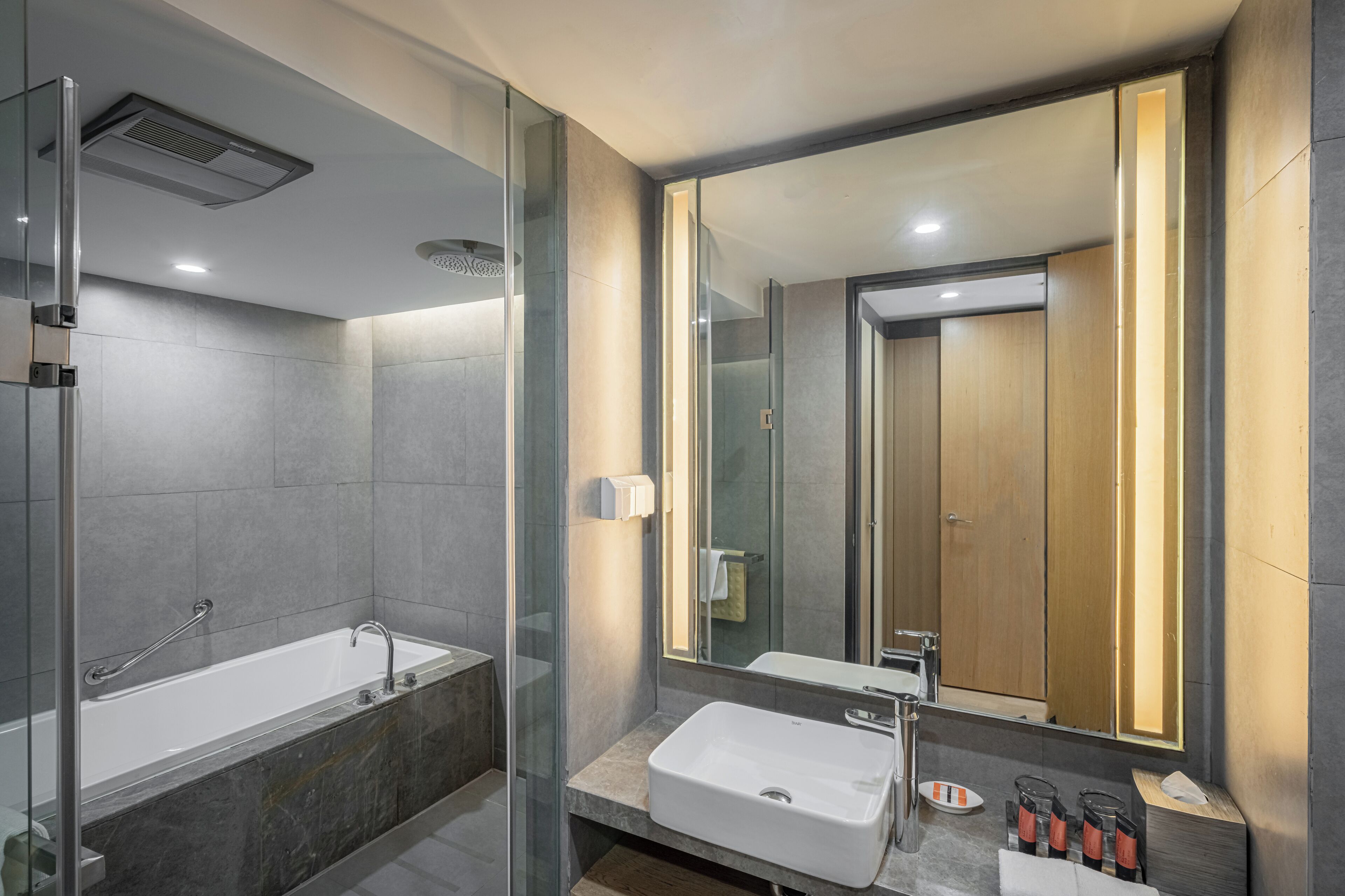 Ein modernes Badezimmer mit einer gläsernen Dusche, einer freistehenden Badewanne und einem Waschtisch mit großem Spiegel.