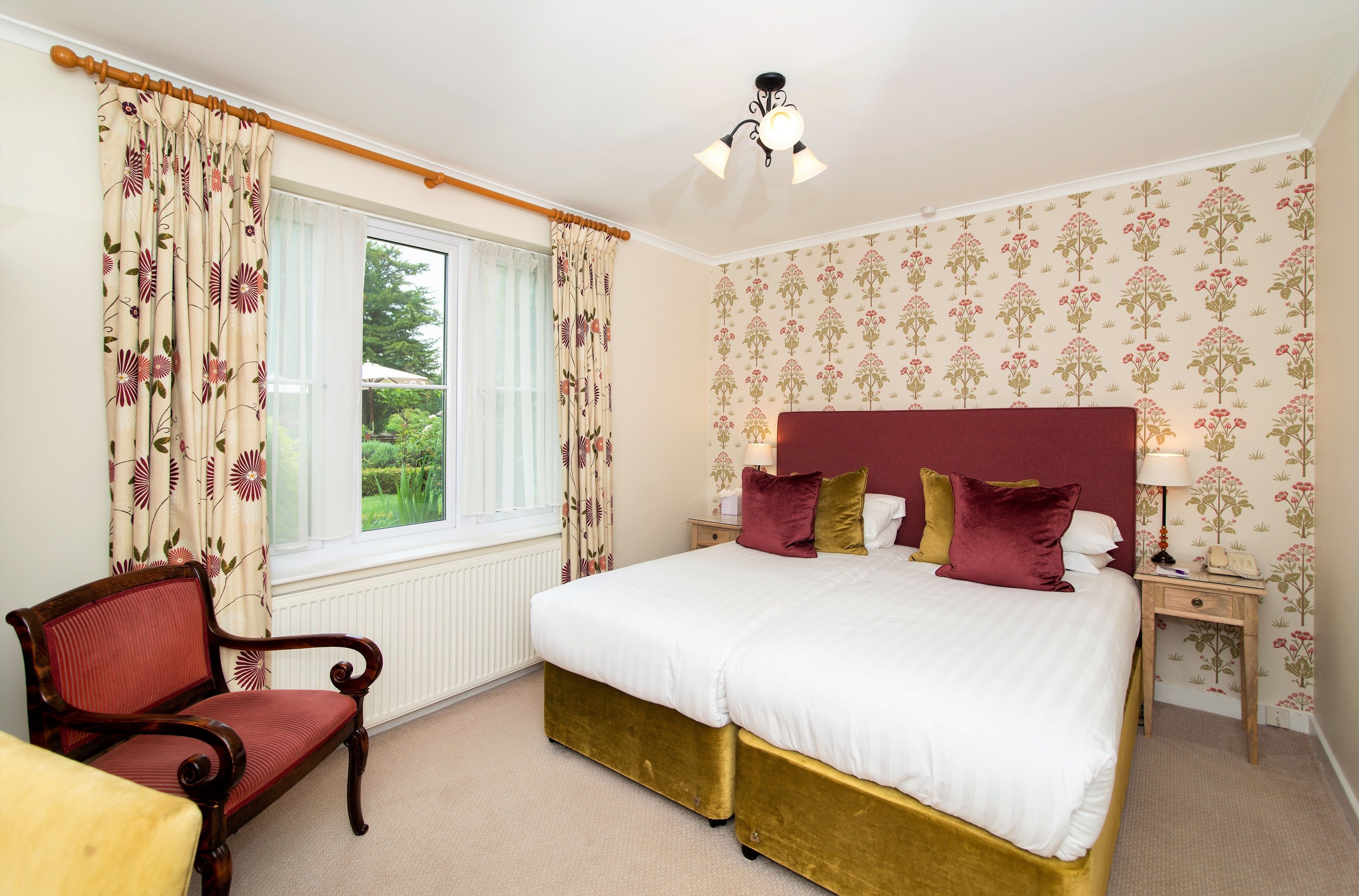 A bedroom with a bed, a chair, a nightstand, and a window with curtains.