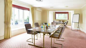 Un salón de conferencias con una gran mesa, sillas, una pizarra y un proyector.