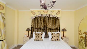 A hotel room with a large bed, two bedside tables with lamps, a chandelier, and a curtain with a pattern.