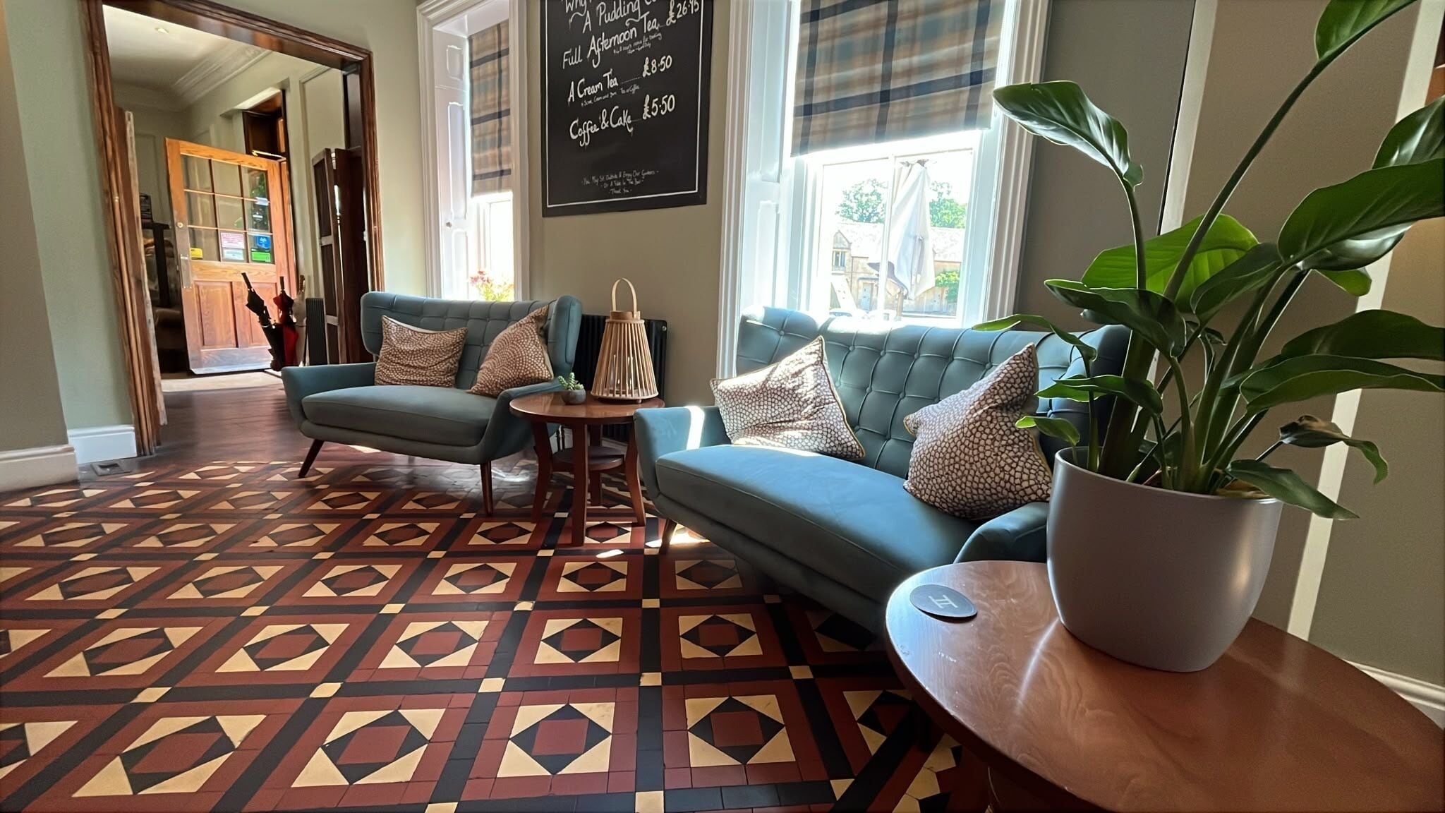 A living room with a patterned floor, a blue sofa, a small table, and a potted plant.
