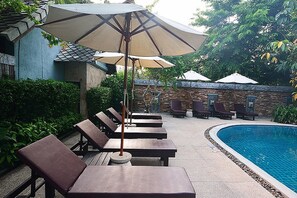 Een buitenzwembad, parasols voor strand/zwembad