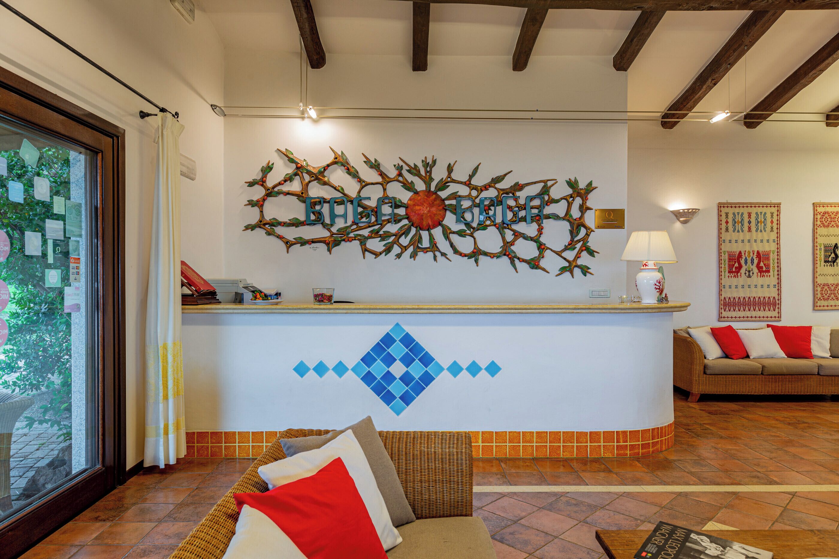 Un mostrador de recepción con un cuadro decorativo, un sofá con cojines y un piso de baldosas.
