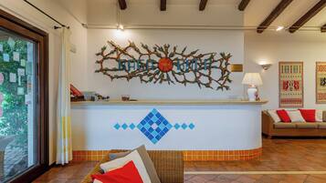 Un mostrador de recepción con un cuadro decorativo, un sofá con cojines y un piso de baldosas.