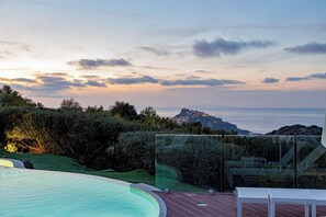 Una piscina con vista al mar y una montaña distante.