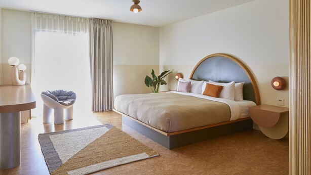 A modern hotel room with a large bed, bedside tables, a desk, and a chair.
