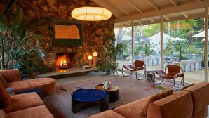 A cozy lounge area with a stone fireplace, comfortable seating, and a view of the outdoor patio.