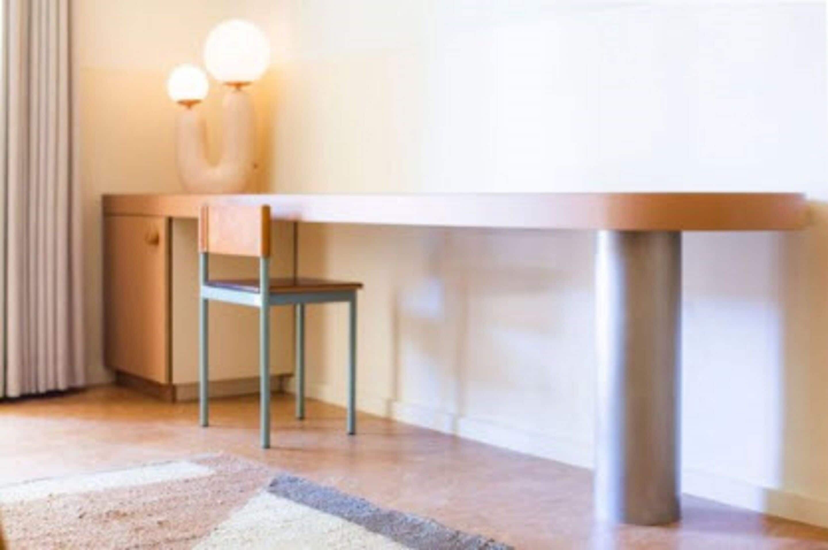 A room with a wooden desk, a chair, and a lamp.