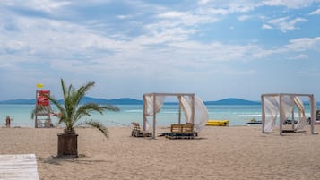 In Strandnähe, weißer Sandstrand, Liegestühle, Sonnenschirme