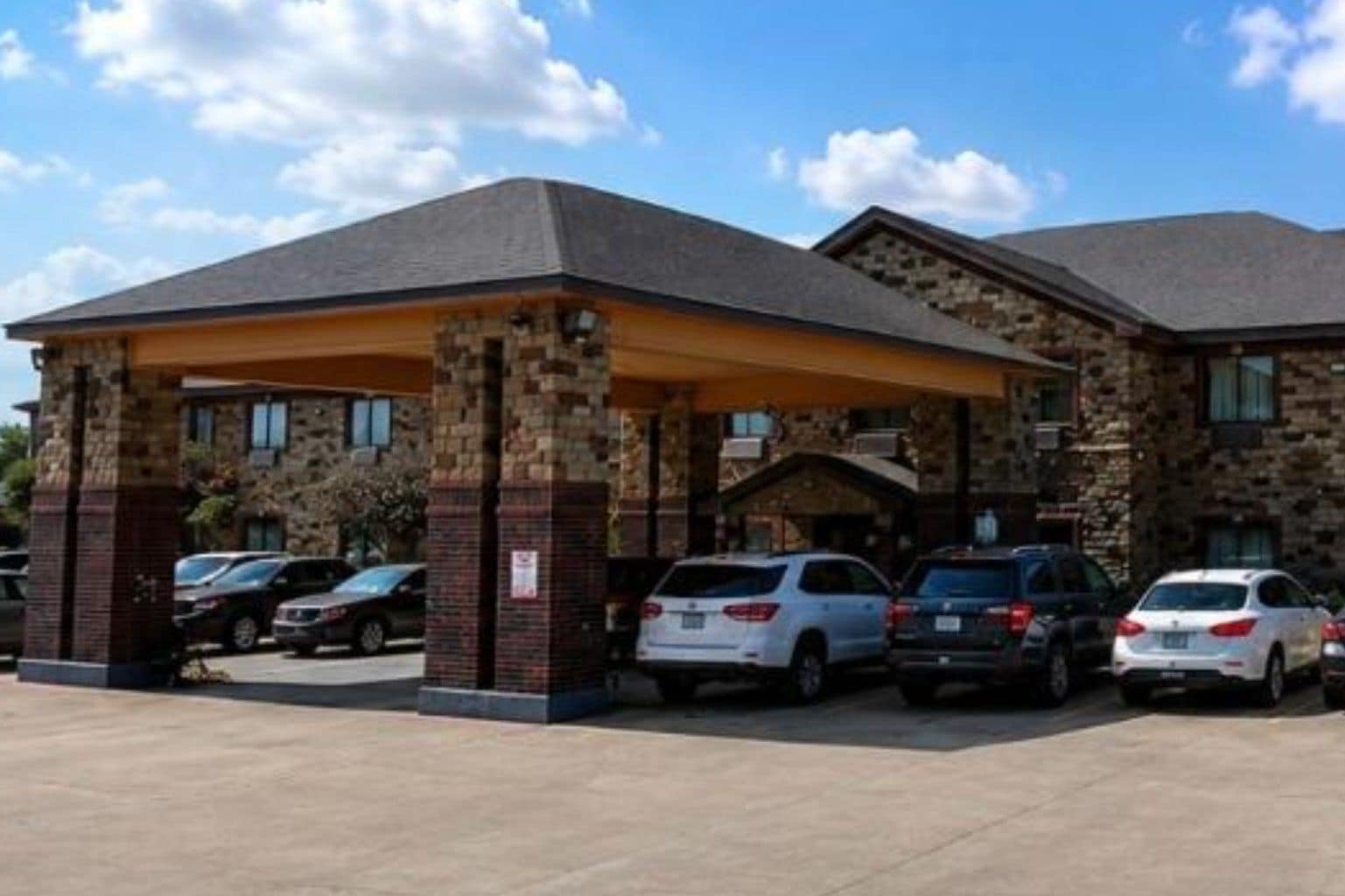 A hotel with a covered parking area and stone facade.