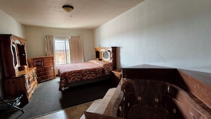 Un dormitorio con cama, cómoda de madera, tocador y bañera.