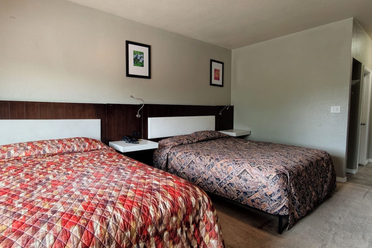 Ein Hotelzimmer mit zwei Betten, einem Nachttisch und einer Wandlampe.