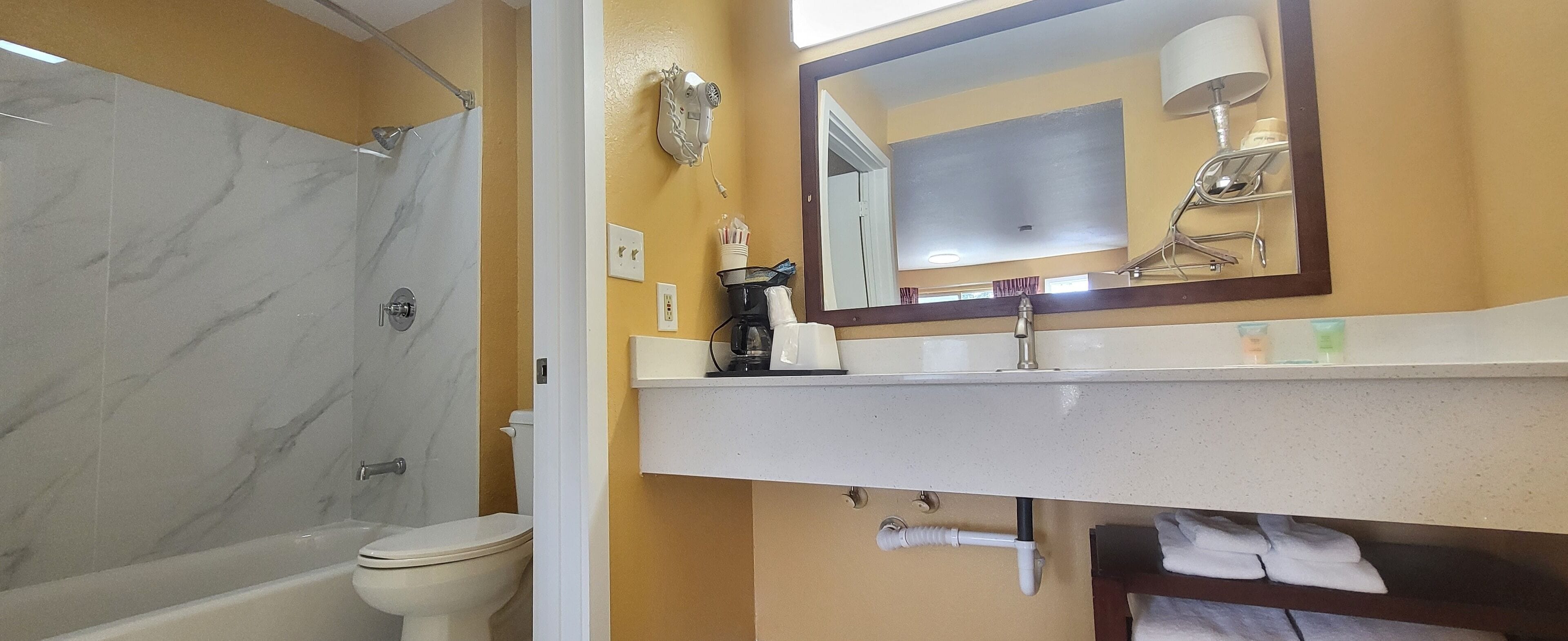 A bathroom with a shower, toilet, sink, and mirror.