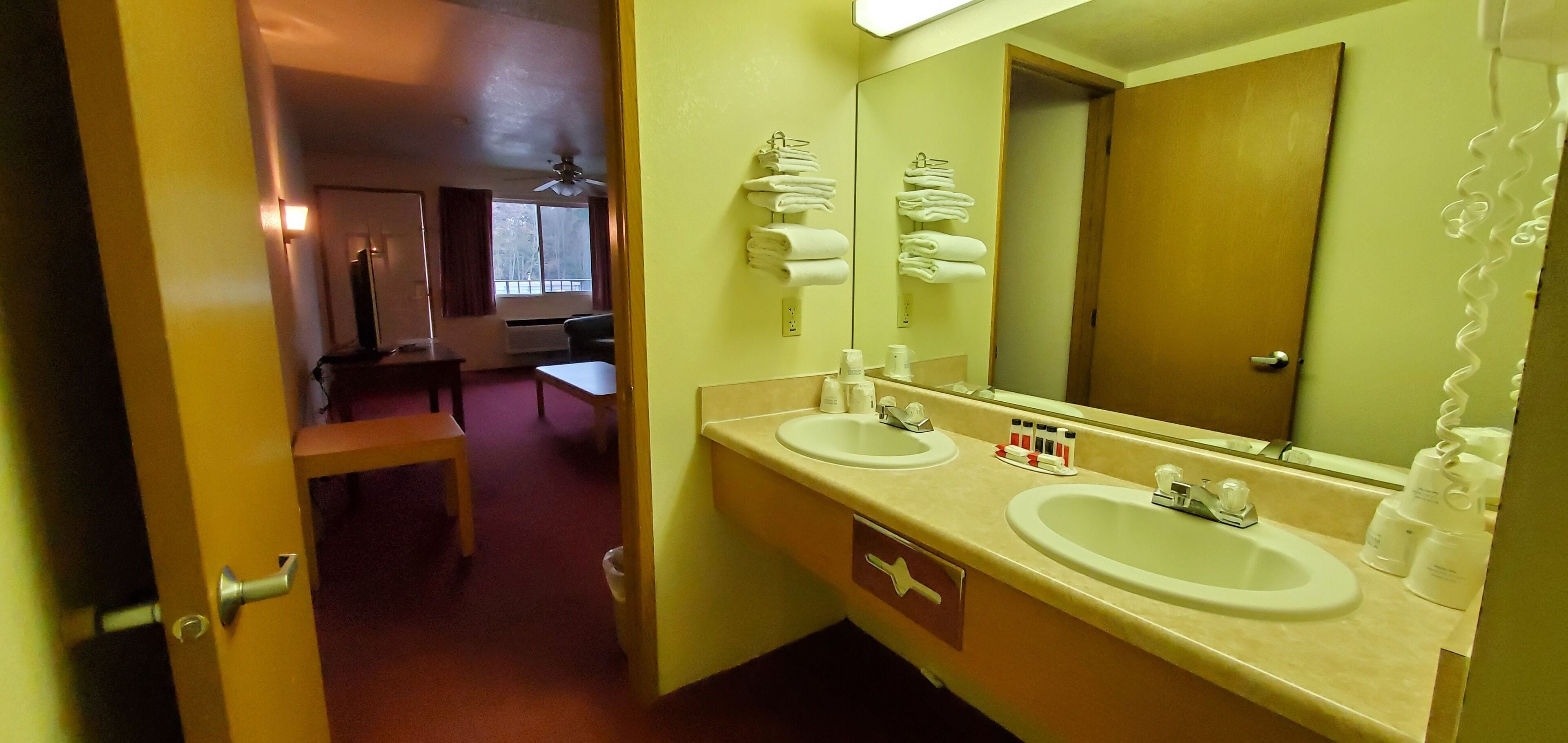 A hotel bathroom with two sinks, a mirror, and a towel rack.