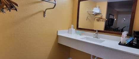 Un baño con lavamanos, espejo, toallero y retrete.