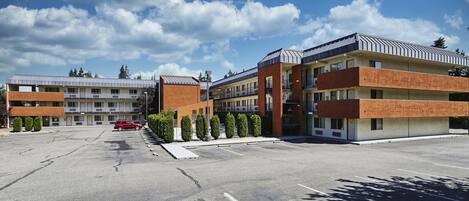 Een hotel met meerdere verdiepingen en een parkeerplaats, met een modern architectonisch ontwerp dat baksteen en metaal combineert.
