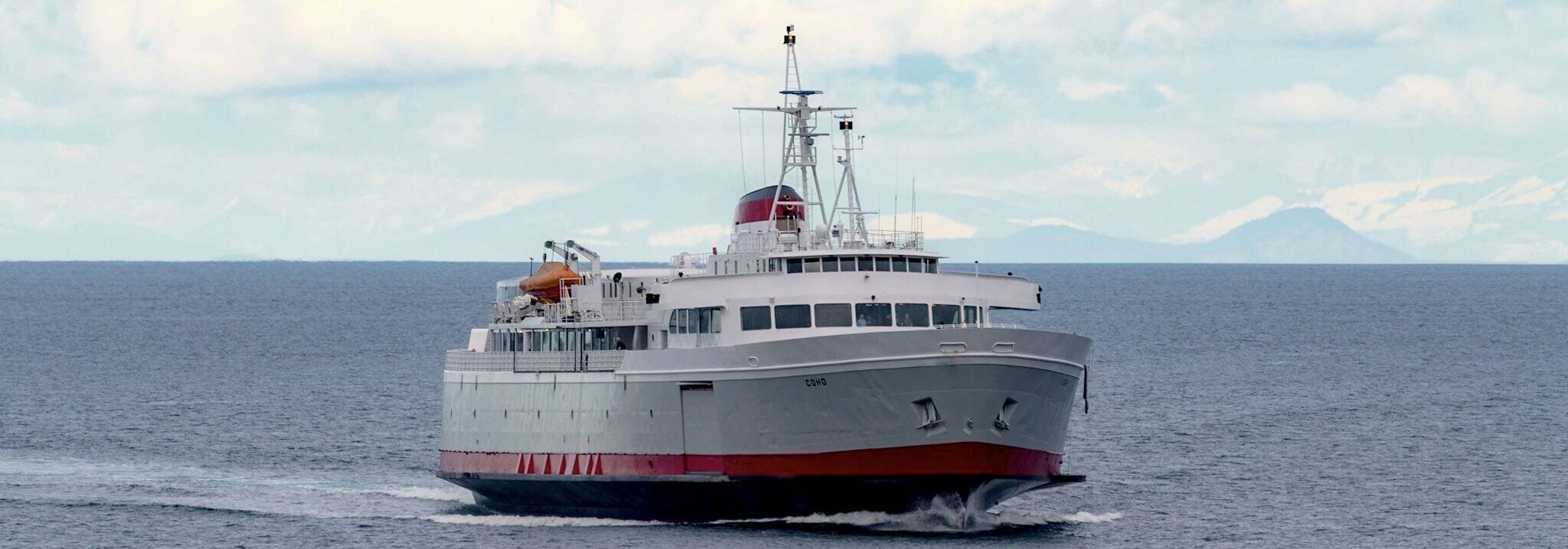 A large, white and red ship with a cabin structure and a funnel, sailing on open water.