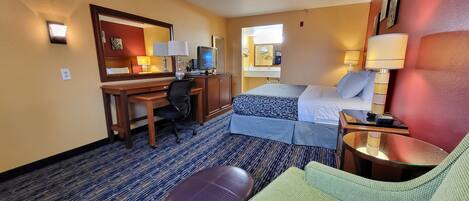 A hotel room with a bed, desk, chair, and a small table.