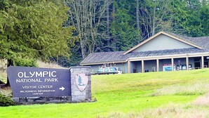 Un panneau indiquant l’emplacement du centre d’accueil du parc national olympique, avec un bâtiment en arrière-plan.
