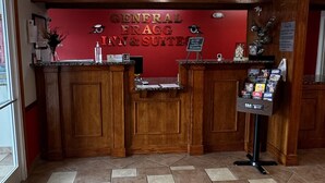 A reception desk with a red wall and wooden paneling. - General Bragg Inn & Suites Chickamauga (Chickamauga)