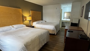 A hotel room with two beds, a desk, a lamp, and a bathroom visible through an open door. - General Bragg Inn & Suites Chickamauga (Chickamauga)