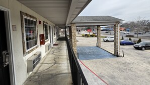 A motel with a covered walkway, a parking lot, and a view of the street. - General Bragg Inn & Suites Chickamauga (Chickamauga)