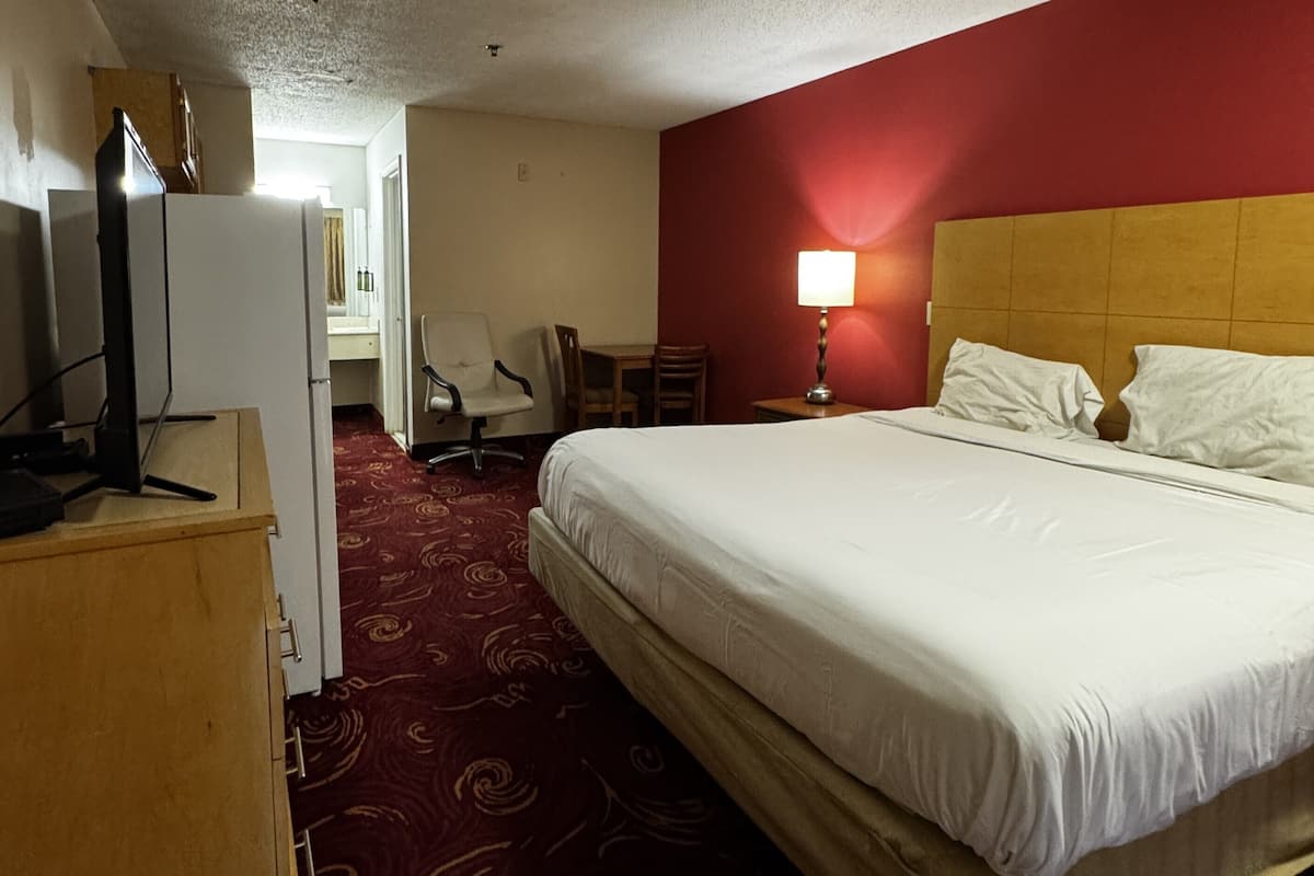 Hotellihuone, jossa on suuri sänky, työpöytä, tuoli ja televisio.