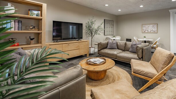 A modern living room with a sofa, armchairs, a coffee table, a TV, and a bookshelf. - La Residence Suite Hotel (Bellevue)