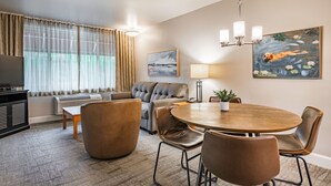 A hotel room with a sofa, a dining table with chairs, a TV, and a painting on the wall. - La Residence Suite Hotel (Bellevue)