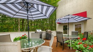 An outdoor patio with a round glass table, white chairs, and striped umbrellas. - La Residence Suite Hotel (Bellevue)
