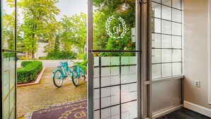 A hotel entrance with a sliding glass door, a bicycle parked outside, and a view of greenery. - La Residence Suite Hotel (Bellevue)