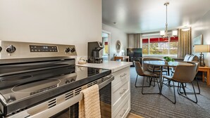 A modern kitchen with a stove, a dining area with chairs and a table, and a window with a view. - La Residence Suite Hotel (Bellevue)