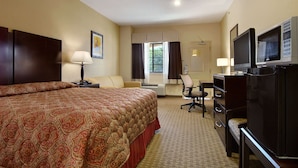 Une chambre d’hôtel avec un grand lit, un bureau avec un ordinateur, une télévision et une chaise.