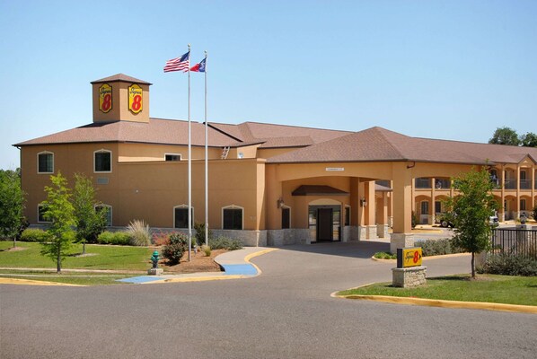 Un hotel con fachada color beige, un asta con dos banderas y un letrero que indica el nombre 'Super 8'.