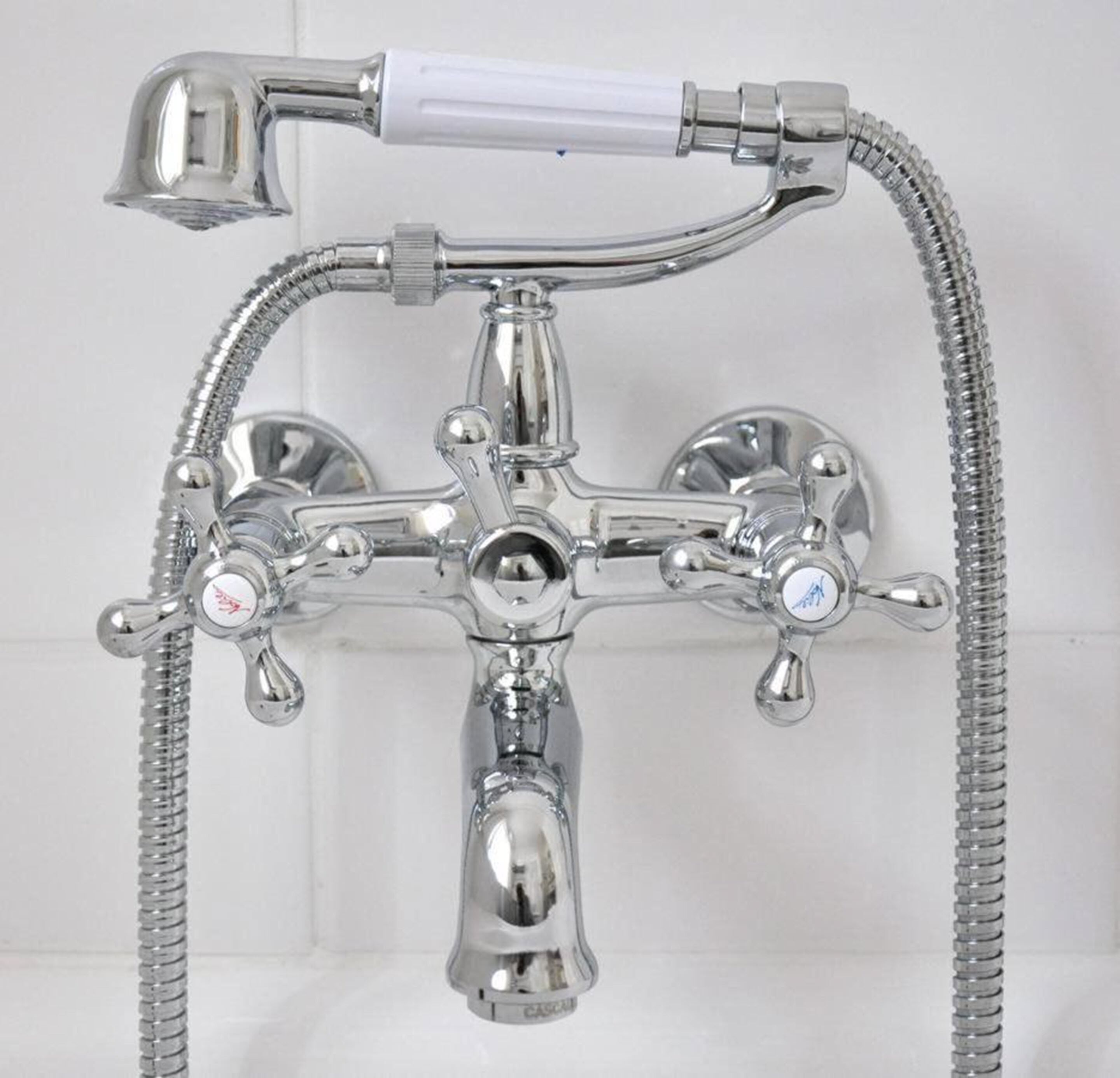 A chrome bathroom fixture with a shower head, two spouts, and a flexible hose.