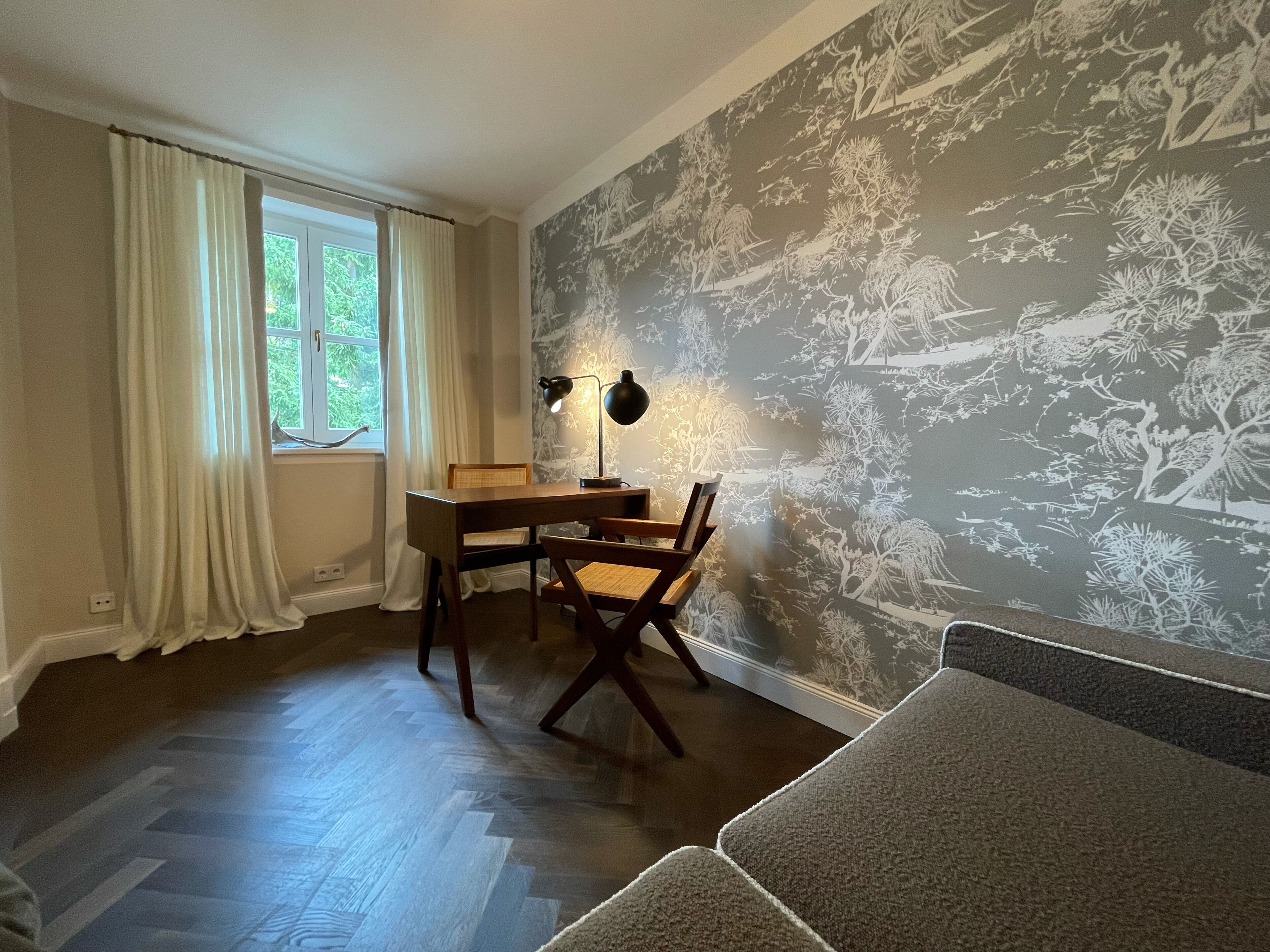 Une pièce avec un bureau en bois, une chaise, une lampe et un papier peint à motifs.