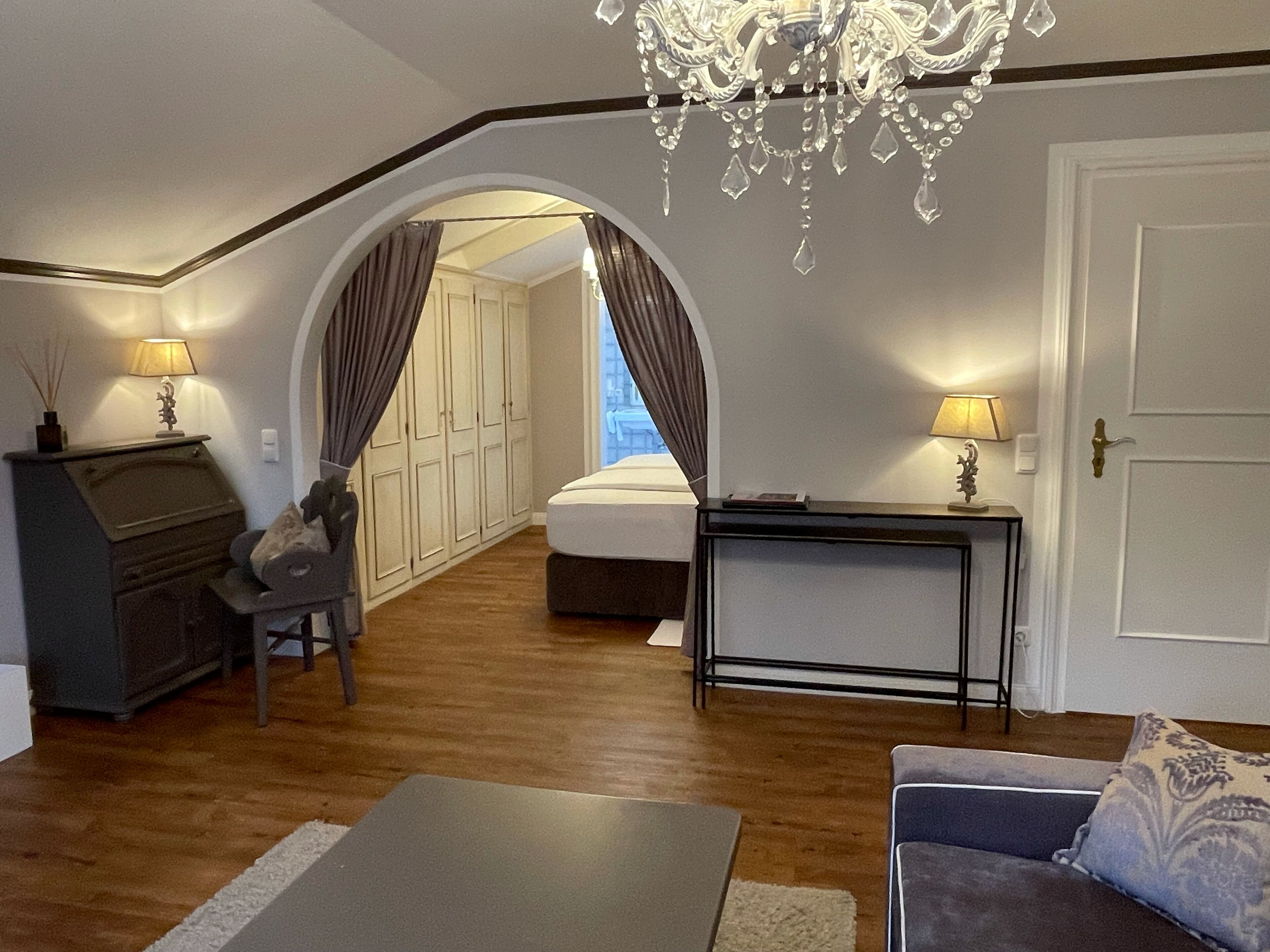Een slaapkamer met een bed, een bureau en een stoel. Achtergrond is een kledingkast en een deur.
