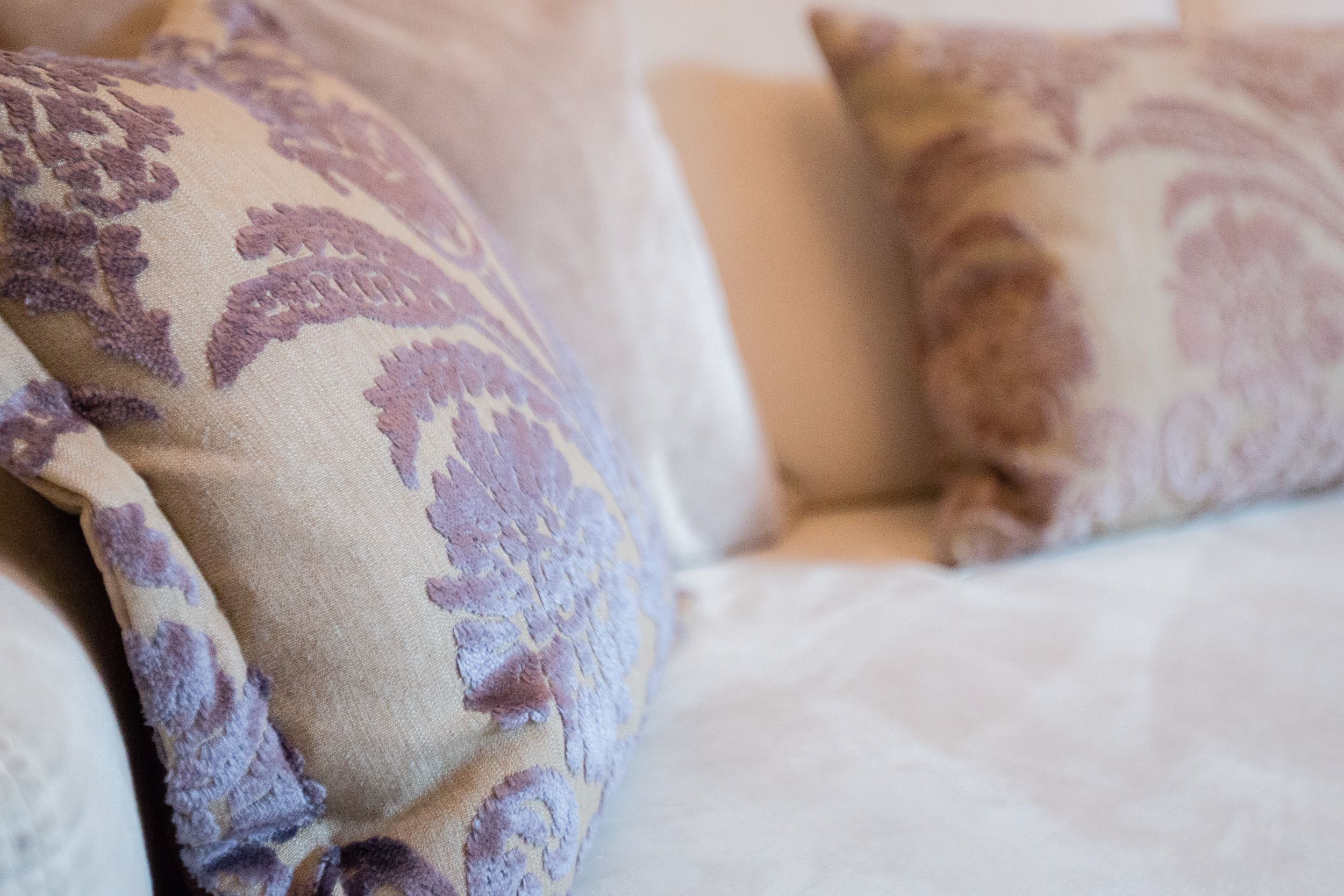 A close-up of a bed with patterned pillows and a white bedspread.