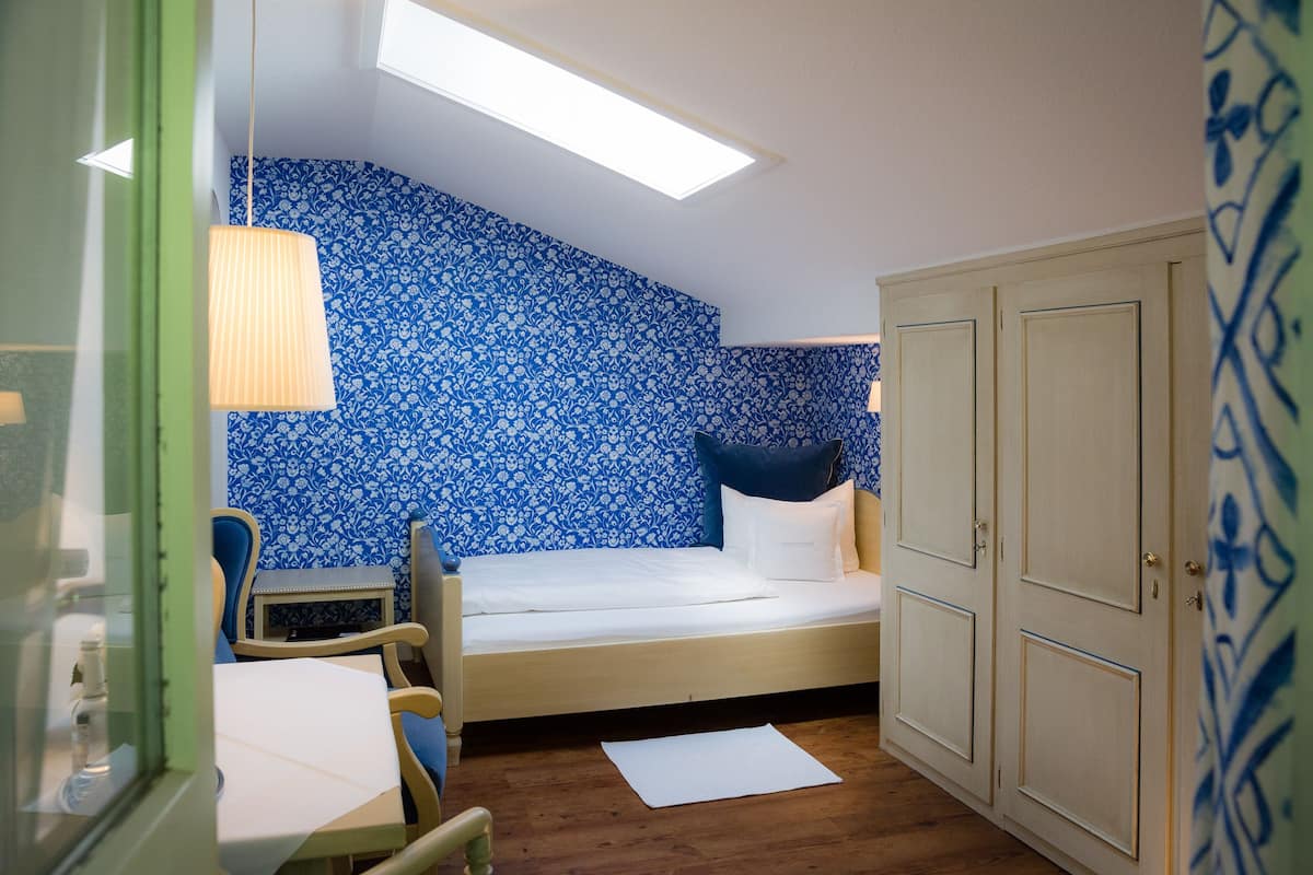 A small room with a bed, a desk, a chair, and a wardrobe.