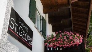 Un edificio con un letrero que dice "Landhaus St. Georg" y una cesta de flores con flores rosas.