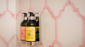 Een badkamer met een wanddispenser met daarin twee flesjes shampoo.