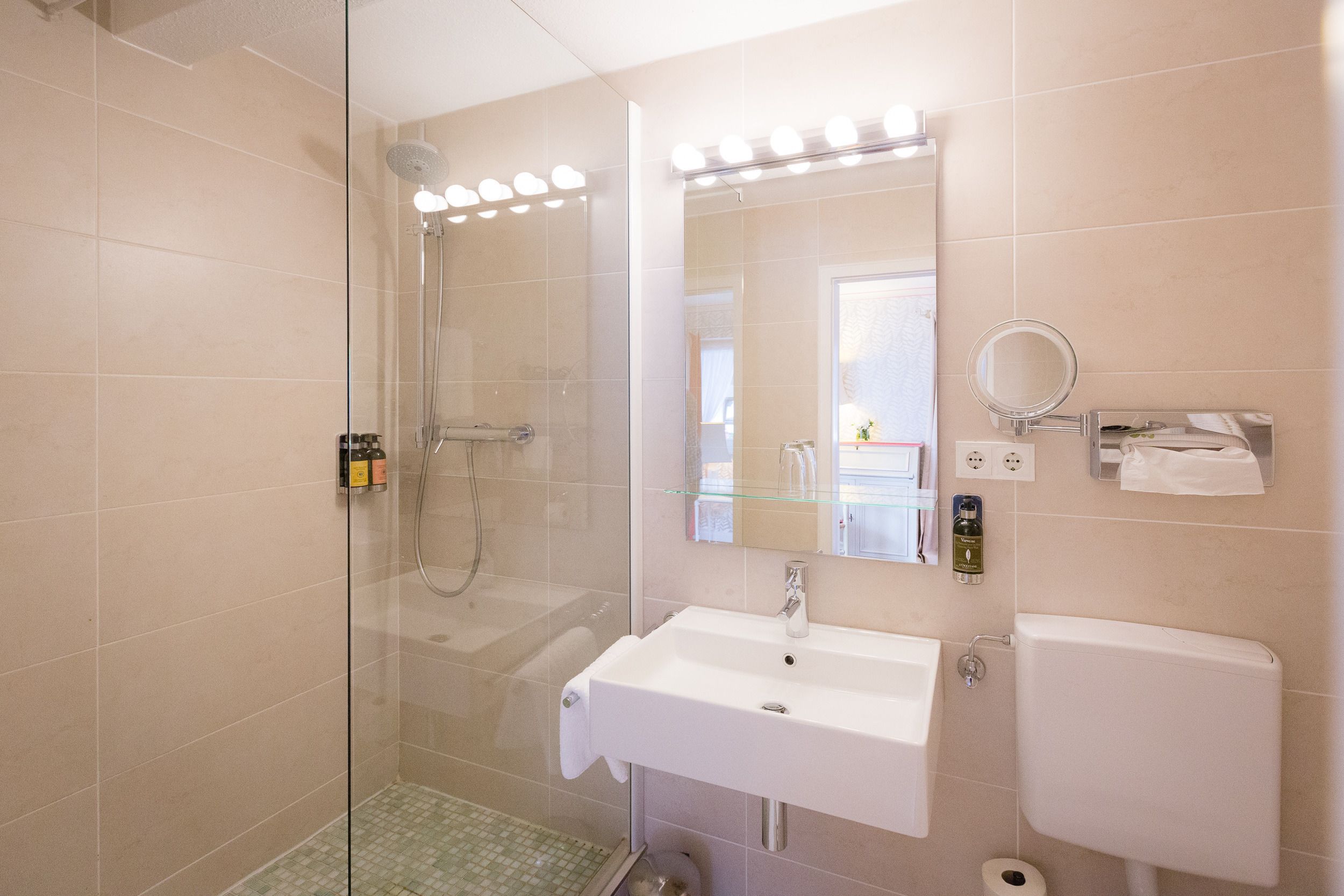 Een moderne badkamer met een douchecabine van glas, een wit wastafelmeubel en een grote spiegel.