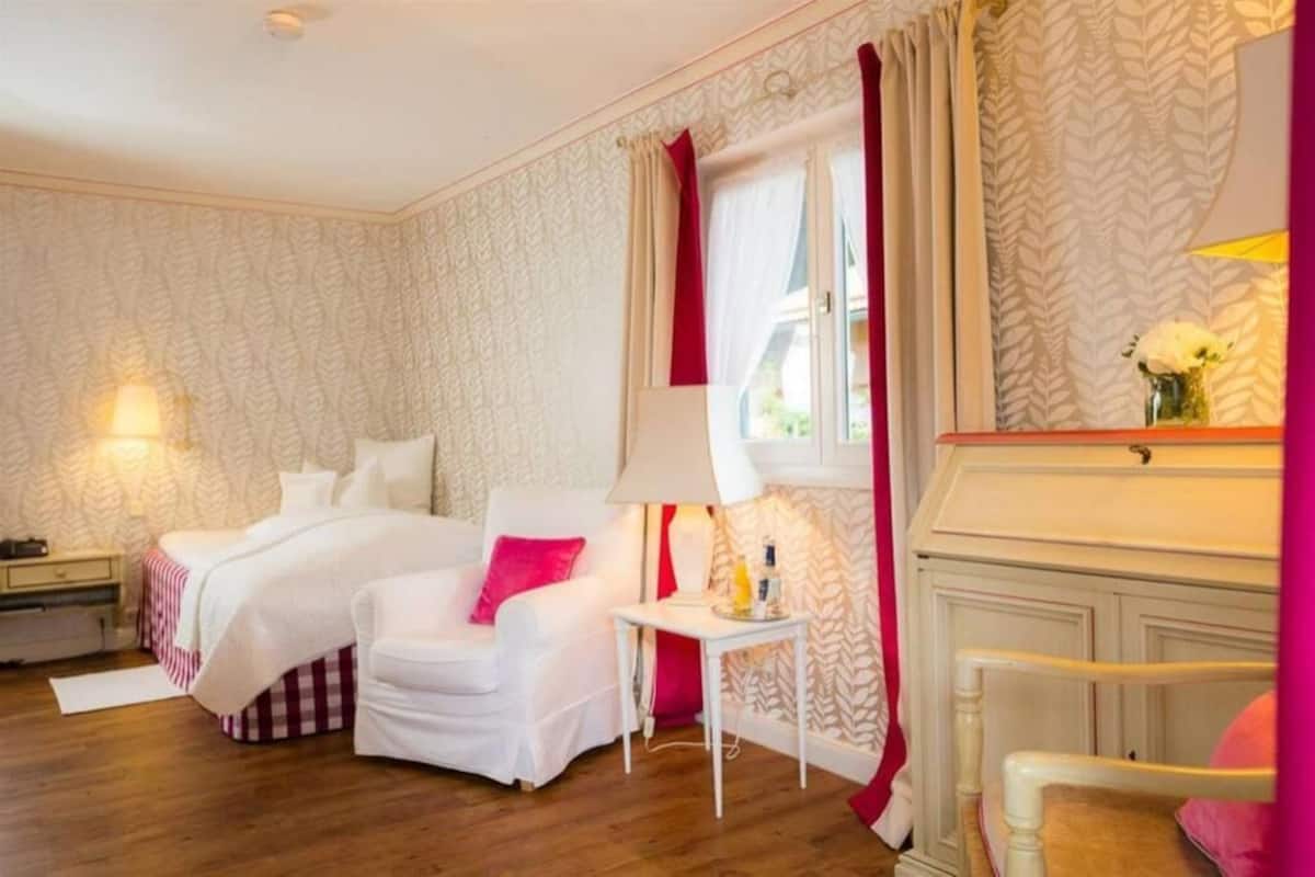 A hotel room with two beds, a small table, a chair, a nightstand, and a mirror.