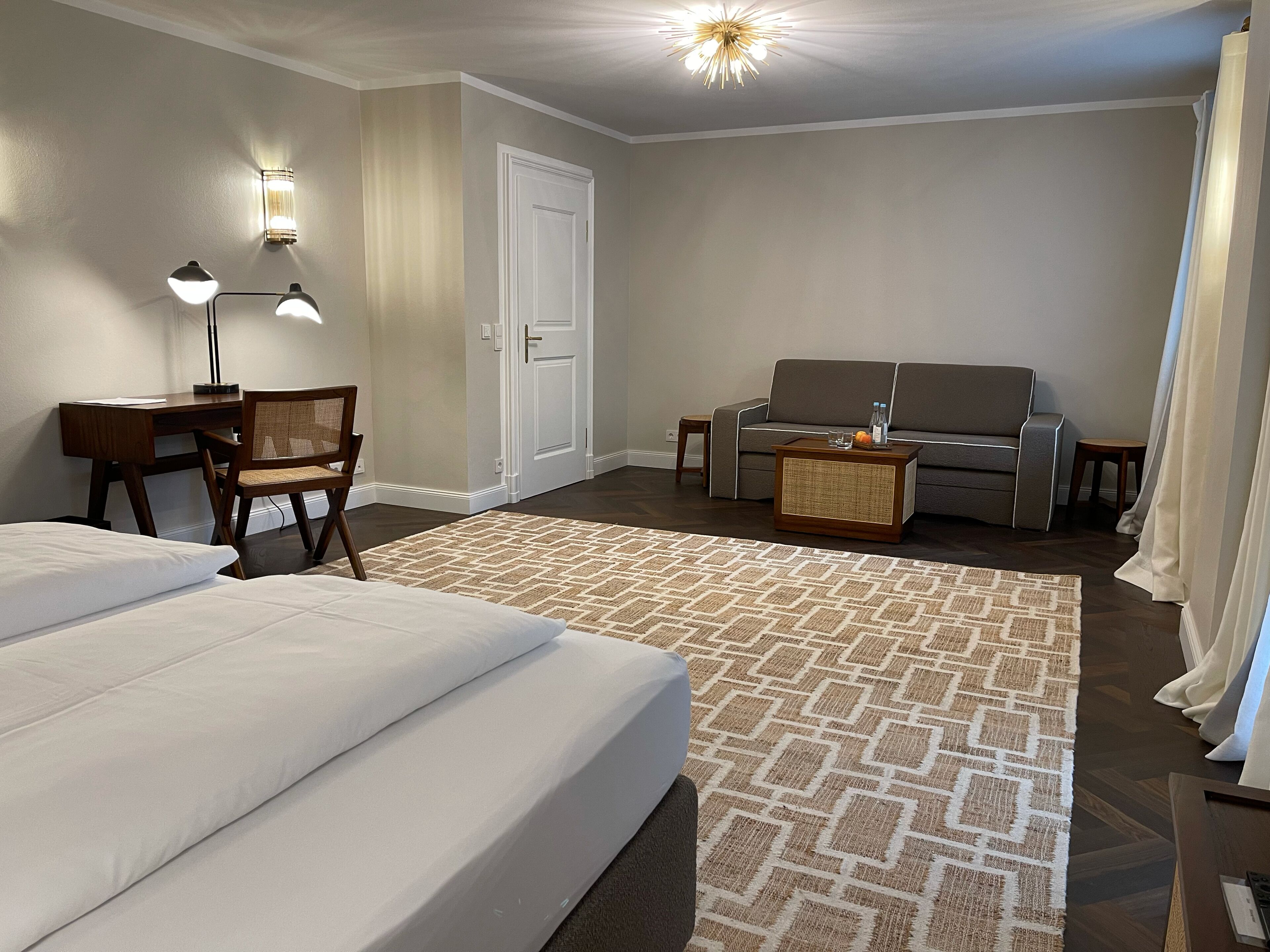 Habitación de hotel con cama, escritorio, sillón, sofá y mesa de centro.