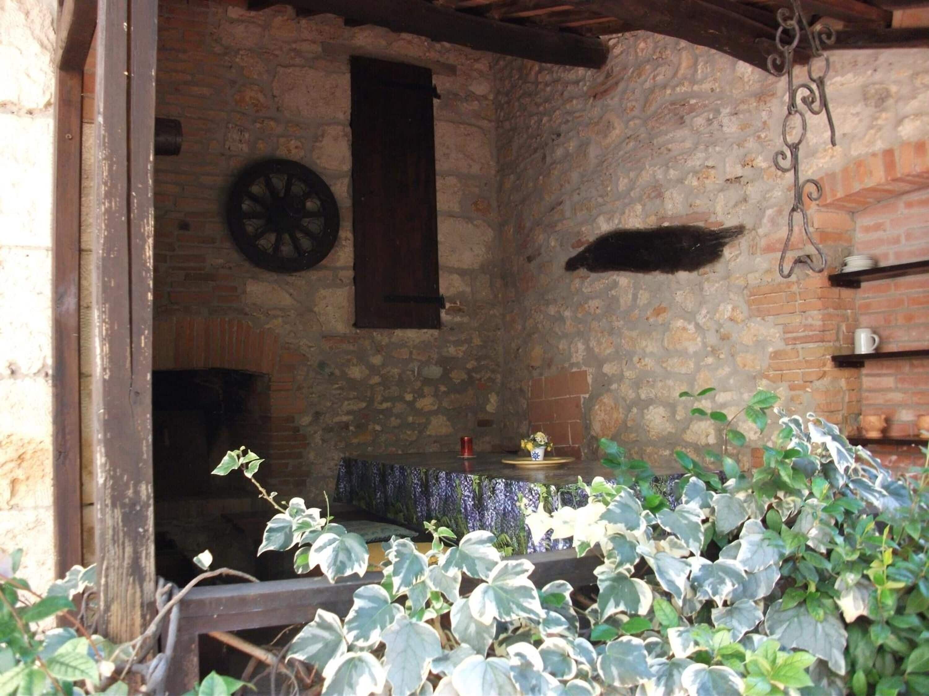 A rustic stone room with a wooden door, a table with a blue tablecloth, and a hanging light fixture.