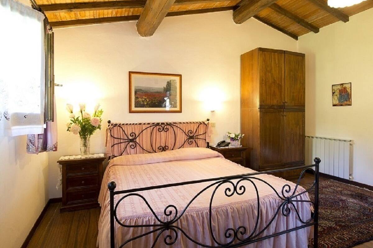 Une chambre à coucher avec un lit, une armoire en bois, une table de chevet, une lampe et un tableau encadré au mur.