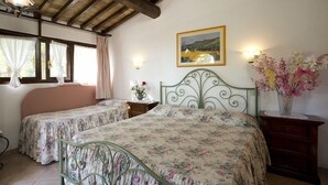 A bedroom with two single beds, a wooden ceiling, a framed picture on the wall, and a vase with flowers on a nightstand. - Hotel Il Pietreto (Colle di Val d'Elsa)