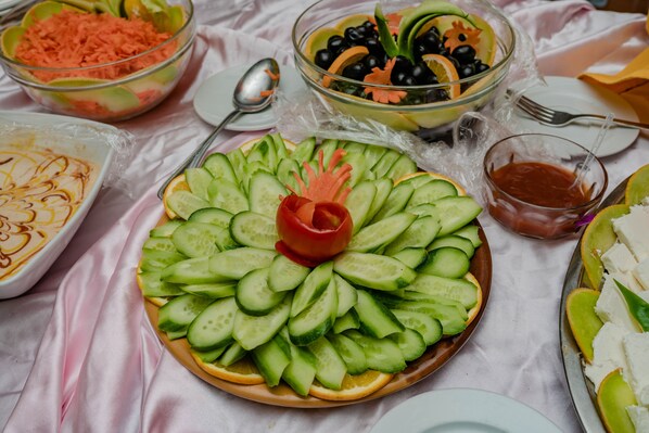 A table with various food items including a cucumber salad centerpiece, bowls of salad, and a dish with cheese.
